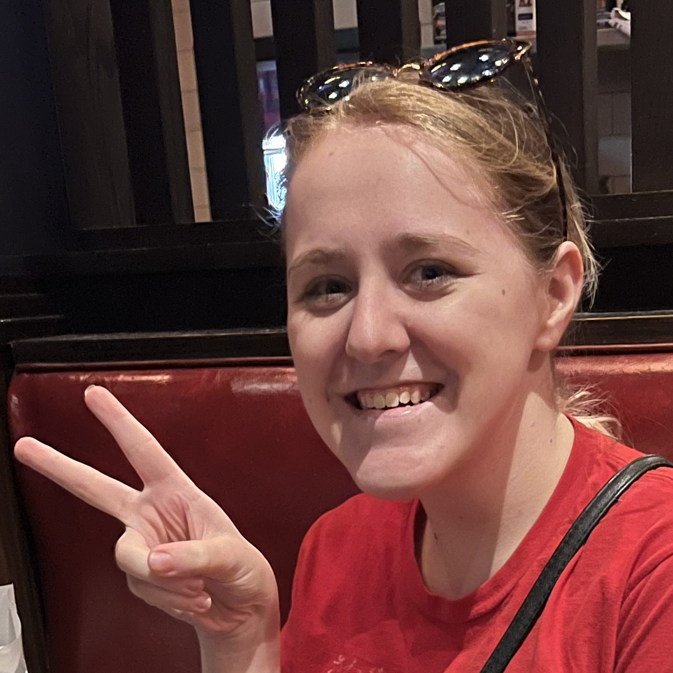 Maysen smiling and making a peace sign in a red shirt